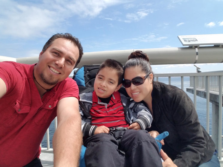 (Father, son in wheelchair and wife smiling)