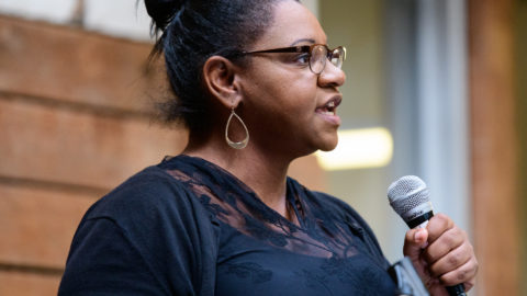 Black woman speaking with a microphone at a conference