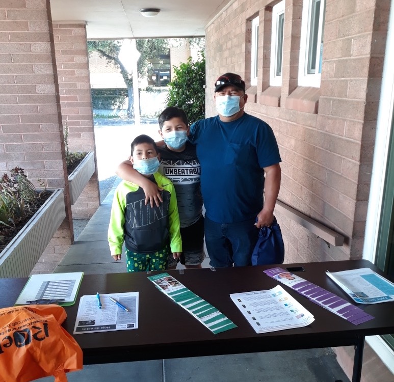 mother father and son with masks on at outreach table